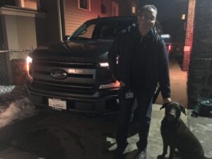 A man and his dog standing next to the truck.
