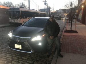 A man standing next to a car on the side of a road.
