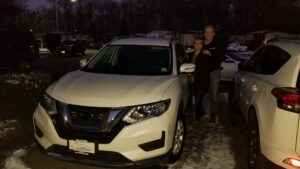 A couple standing next to a white car.