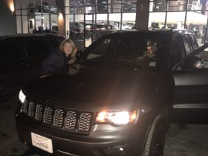 A woman and man sitting in the drivers seat of a jeep.