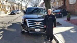 A man standing next to a black car on the street.