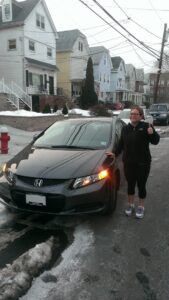 A woman standing next to her car on the street.
