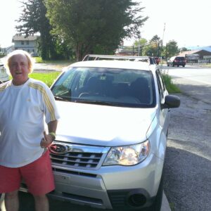 A man standing next to a silver car.