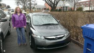 A woman standing next to a car on the street.