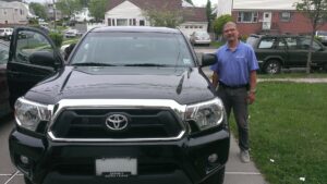 A man standing next to a black truck.