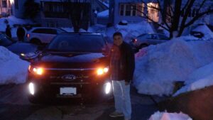 A man standing in front of a car on the street.