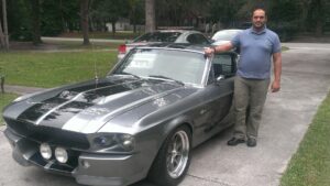 A man standing next to an old car.