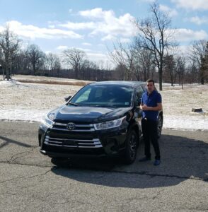 A man standing next to a black car.