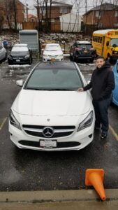 A man standing next to a white car in a parking lot.